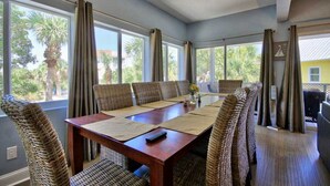 A dining area with a large table, wicker chairs, and a ceiling fan.