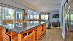 A spacious kitchen with a large island, wooden cabinets, and a ceiling fan.