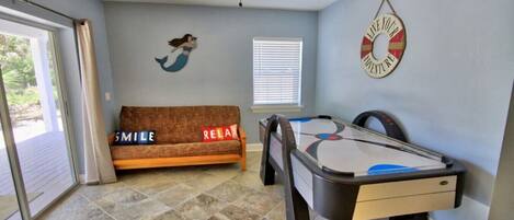 A room with a pool table, a sofa with 'SMILE' and 'RELAX' pillows, a mermaid mural, and a 'LAKE JOY AQUARIUM' sign.