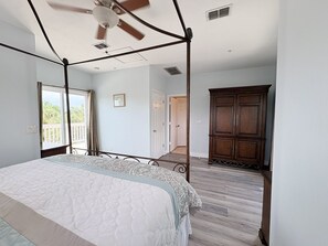 A bedroom with a four-poster bed, a ceiling fan, and a view of the outdoors.