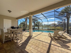 Un porche techado con piscina, mobiliario exterior y vista a un campo de golf.