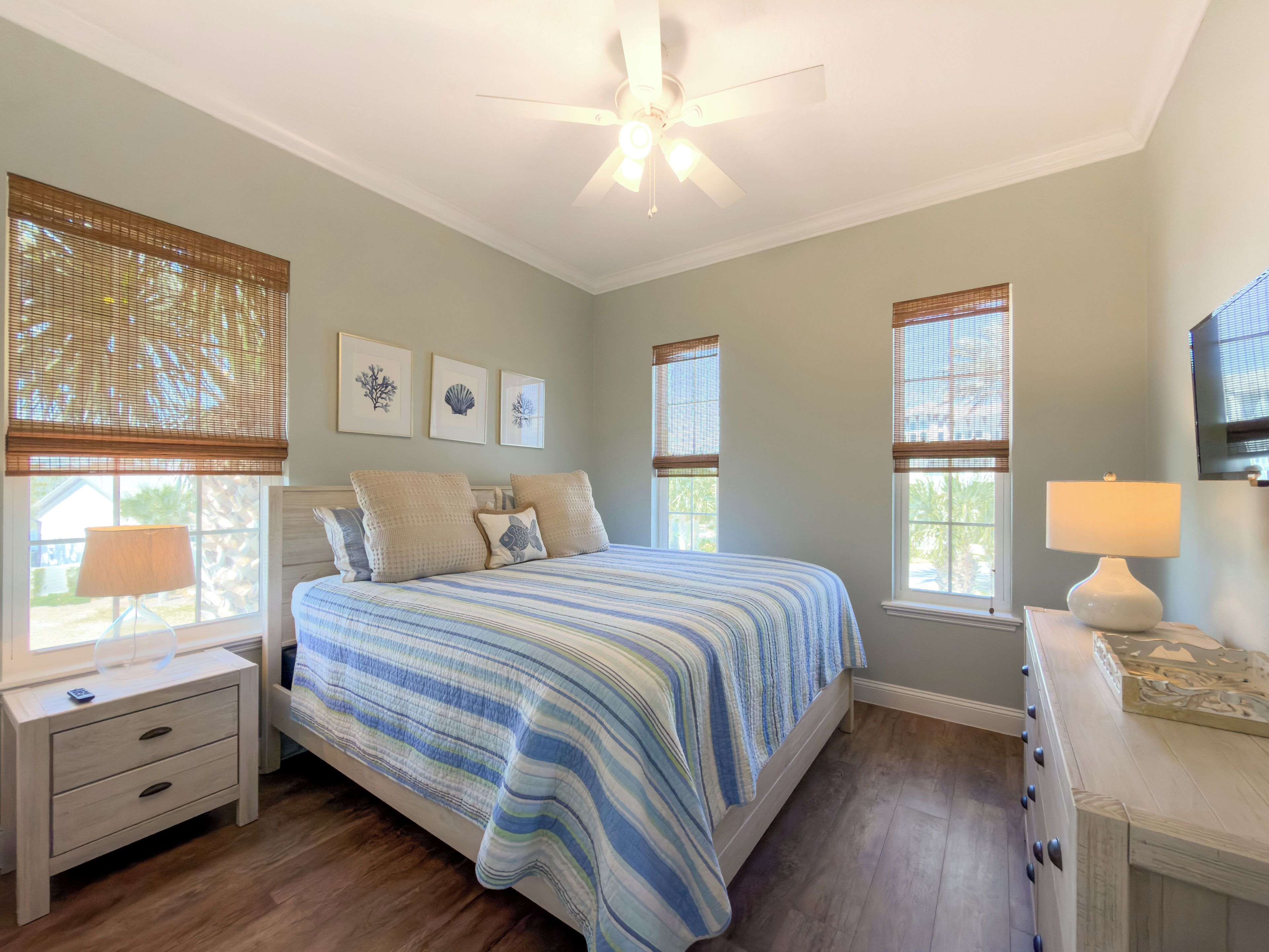 A bedroom with a bed, nightstands, a ceiling fan, and windows with blinds.