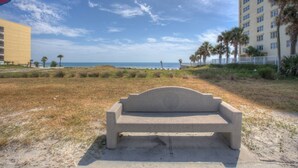 Een betonnen bank in een grasveld met uitzicht op het strand en de oceaan.
