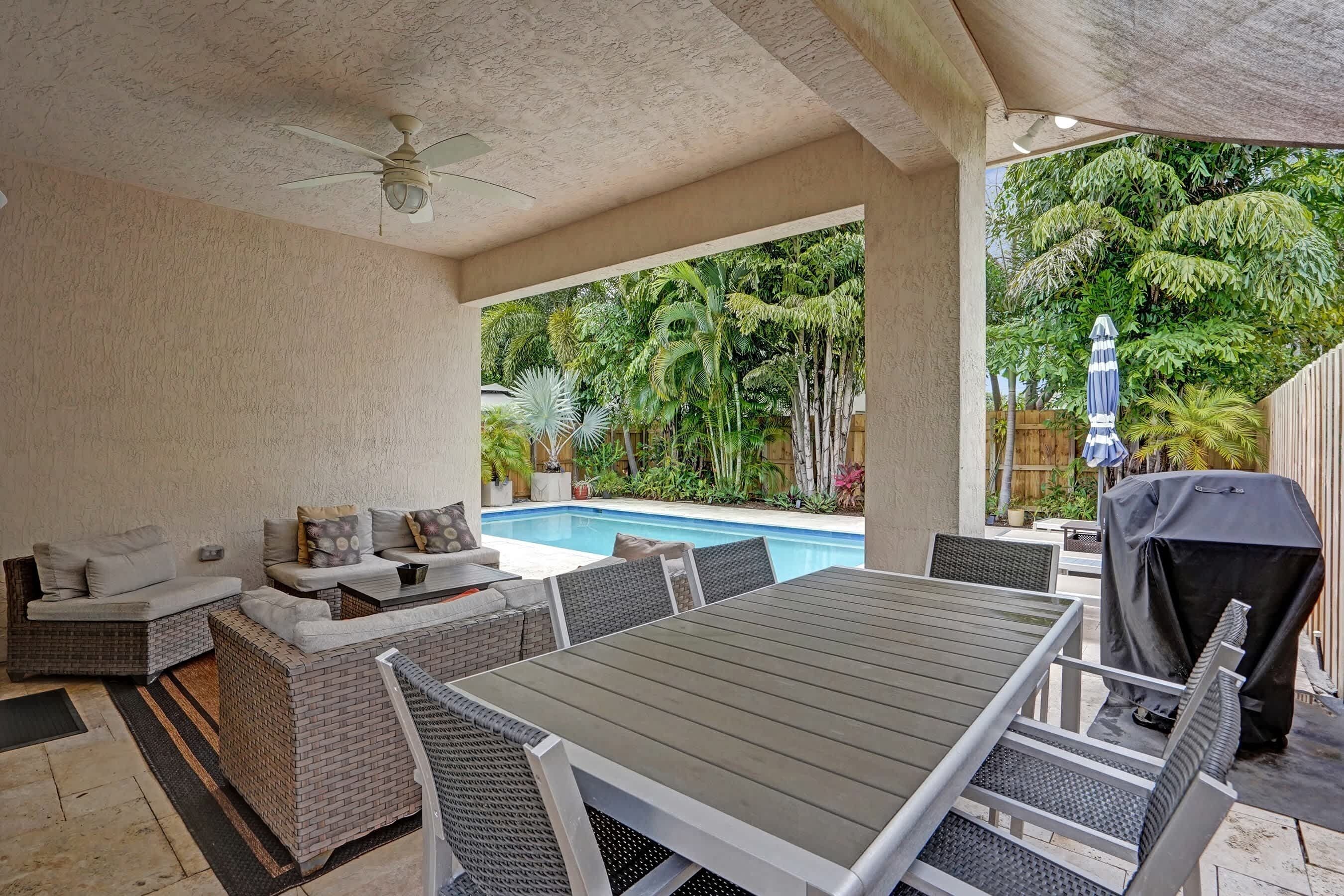 An outdoor patio with a pool, seating area, and grilling station.