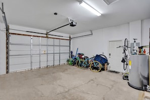 Un garage avec une porte fermée, un projecteur fixé au plafond et des vélos garés à l’intérieur.