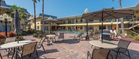 A poolside area with outdoor seating and a barbecue grill.