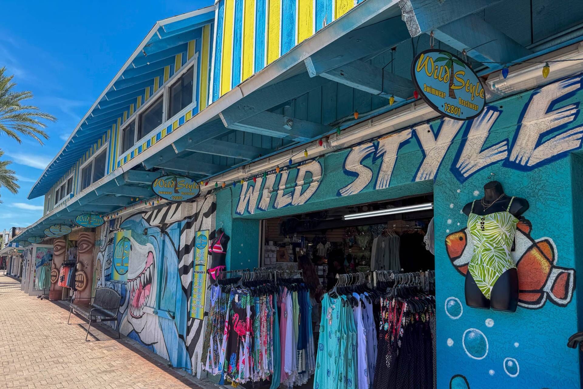 A storefront with a vibrant mural and a variety of colorful swimwear displayed outside.