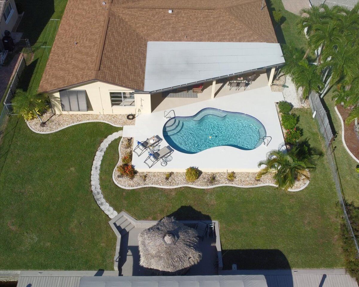 Ein Haus mit Schwimmbad, einer Terrasse mit Stühlen und einem strohgedeckten Aufbau.
