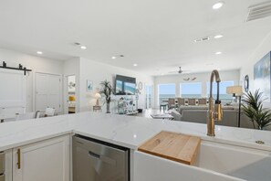 Una cocina moderna con encimera de mármol, lavavajillas y tabla de cortar de madera.