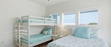 A bedroom with bunk beds, a single bed, a nightstand, a lamp, and a ceiling fan.