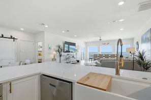 A modern kitchen with a marble countertop, stainless steel appliances, and a wooden cutting board.