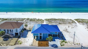 A beachfront property with two buildings, a road, and a sandy beach.