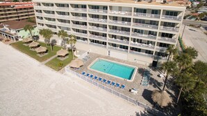 Un hotel de varios pisos con balcones, piscina y zona de playa.