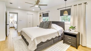 A bedroom with a bed, bedside tables, a ceiling fan, and a window with curtains.