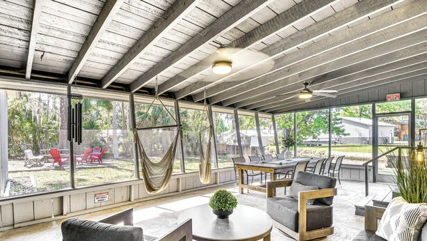 An open-plan living area with a high ceiling, large windows, and outdoor seating.