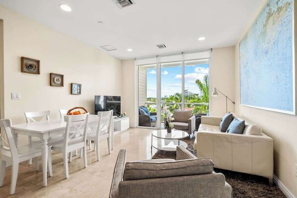 A spacious living room with a dining area, a sofa, and a television.