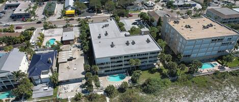 An aerial view of a coastal hotel with multiple buildings, a swimming pool, and surrounding greenery.