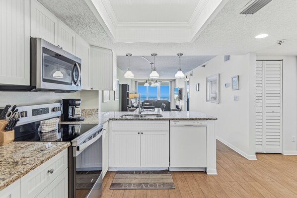 A kitchen with white cabinetry, a built-in microwave, a coffee maker, and a view to the outside.