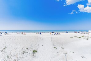 A beach with people sunbathing and swimming, and a clear blue sky.