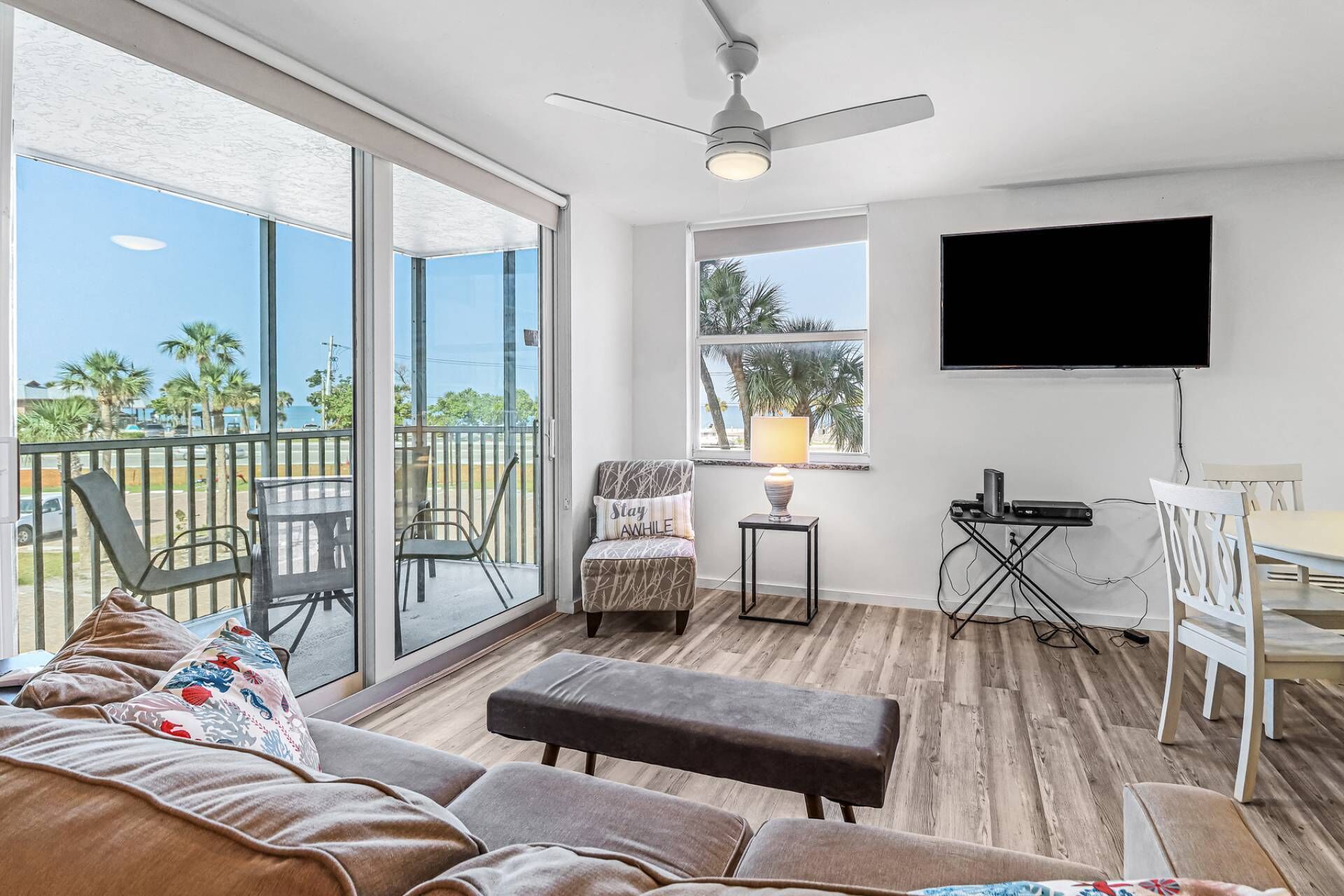 A spacious living area with a balcony, a flat-screen TV, and a seating area with a sofa and chairs.
