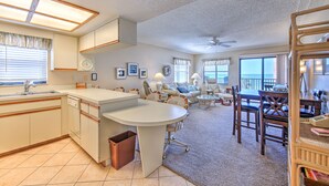 A spacious living area with a kitchen, dining table, and a view of the ocean.