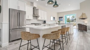 A modern kitchen with stainless steel appliances, a large island with bar stools, and pendant lighting. - Pearl Cottage Private Heated Pool Home! Newly renovated book today! (Palm Coast)