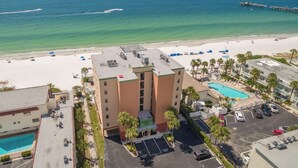A hotel with a rooftop pool, a beach view, and a parking area.