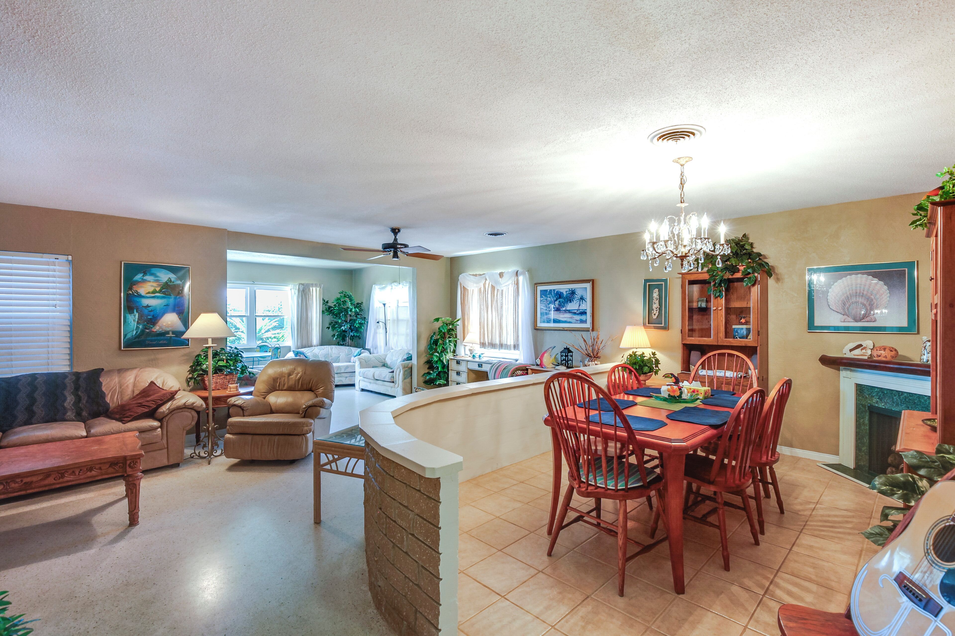 A spacious living area with a dining table, chairs, and a fireplace. There is a sofa and a coffee table in the living room.