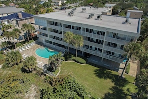 A multi-story hotel with a rooftop pool, balconies, and a well-maintained lawn.
