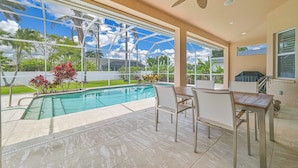 A pool area with a glass enclosure, outdoor seating, and a ceiling fan.