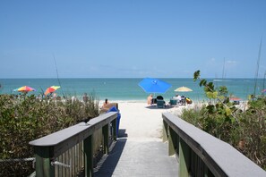 A wooden boardwalk leading to a beach with colorful umbrellas and lounge chairs. - Private Gem - 2 Miles to Beaches! Private Heated Pool - Gorgeous Updated Home (BONITA SPRINGS)