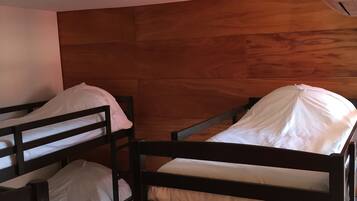 A room with bunk beds, wooden headboard, and a ceiling-mounted air conditioner.