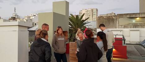 Un grupo de personas en una terraza en la azotea con un paisaje urbano de fondo.