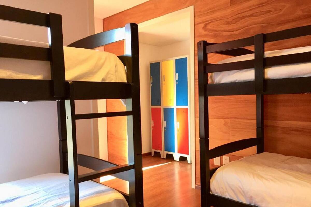 A bunk bed room with wooden walls and a colorful locker area in the background.
