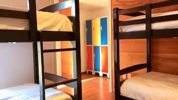Habitación con literas, paredes de madera y una zona de lockers colorida al fondo.