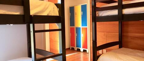 A bunk bed room with wooden walls and a colorful locker area in the background.