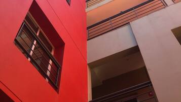 Um edifício de vários andares com fachada vermelha e varandas.