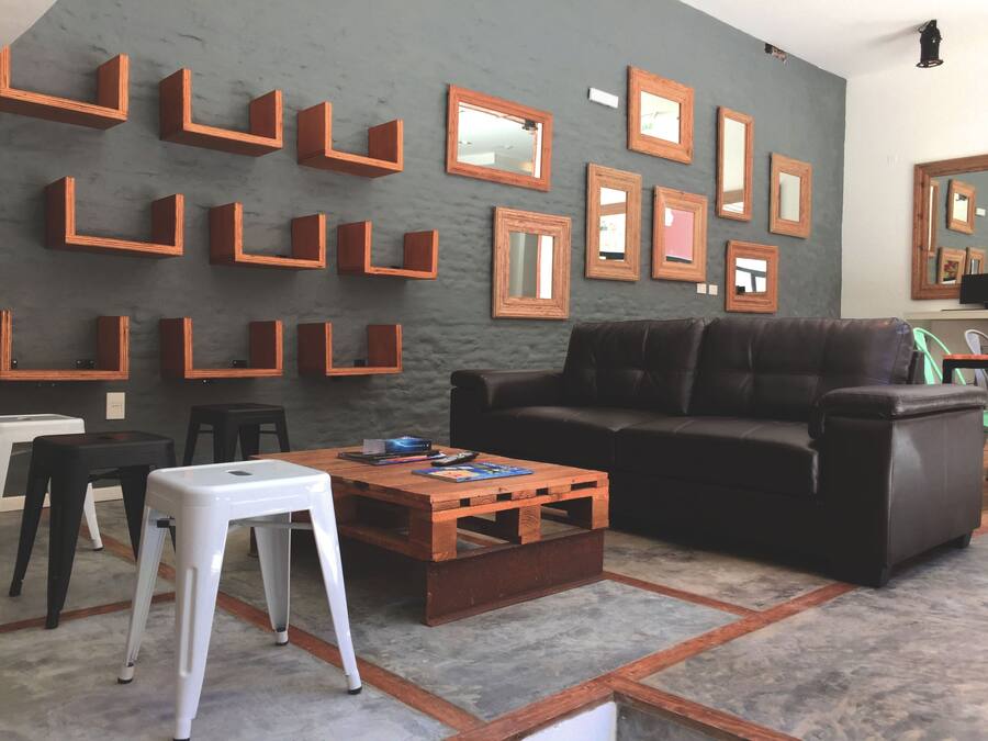 A living room with a brown leather couch, a wooden coffee table, and multiple wooden shelves with mirrors.