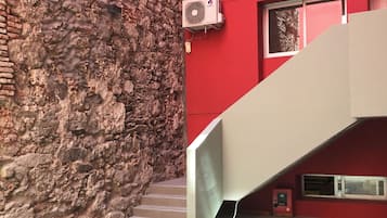 Una escalera que conduce a un edificio rojo con un muro de piedra a un lado.