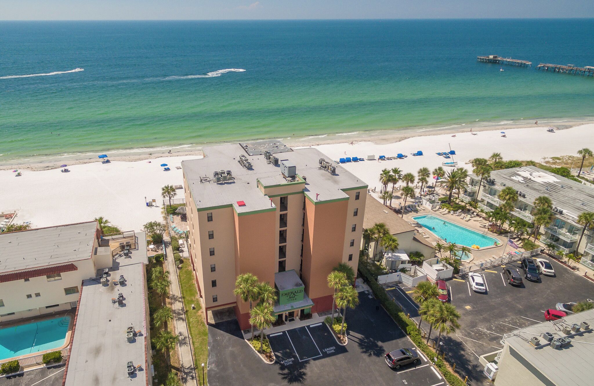 A hotel with a rooftop pool, a beach view, and a parking area.