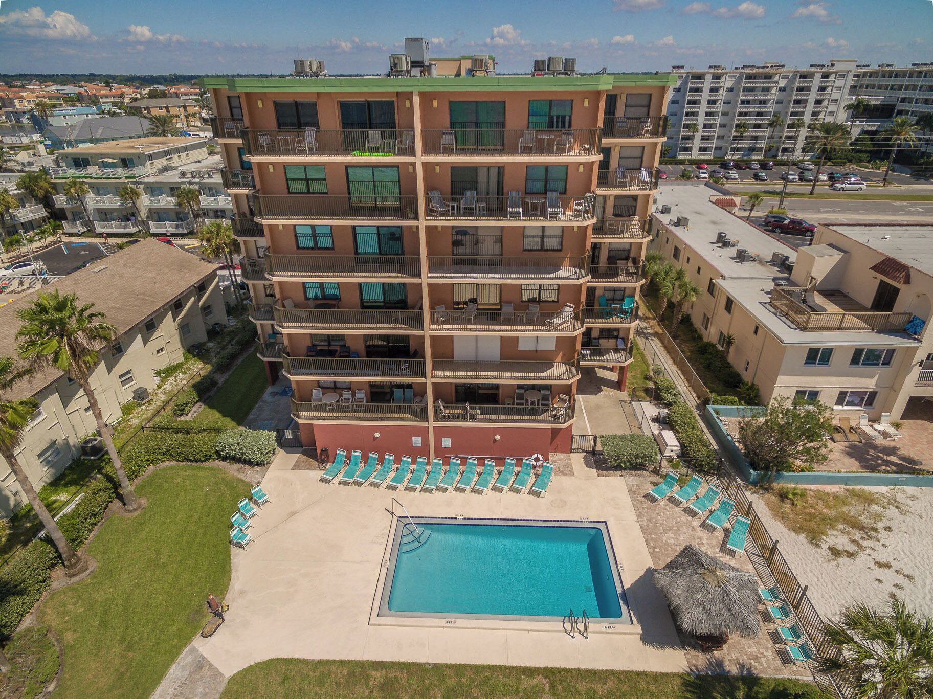 A multi-story hotel with a rooftop pool, outdoor seating, and a view of the surrounding neighborhood.