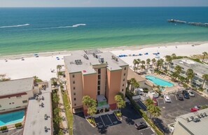 A hotel with a rooftop pool, a beach view, and a parking area.