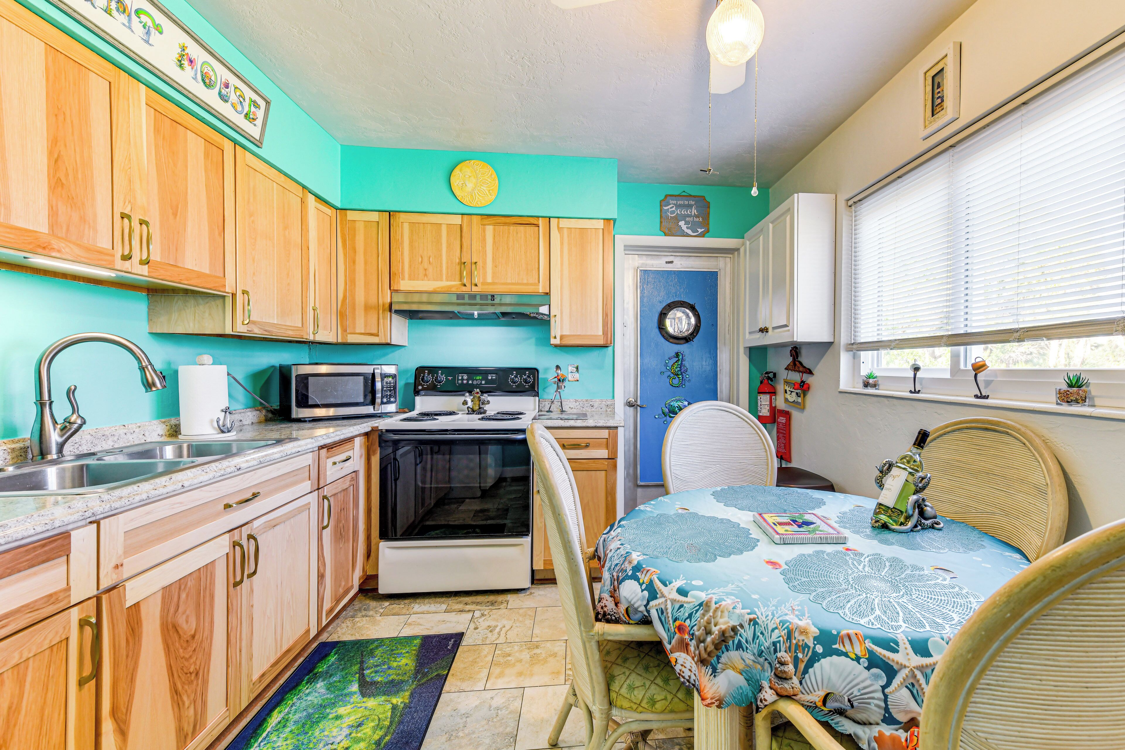 A compact kitchen with wooden cabinets, a microwave, stove, and a dining area with a table and chairs.