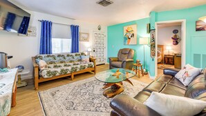 Een woonkamer met een bank, een glazen salontafel, een leren bank en een blauw gordijn.