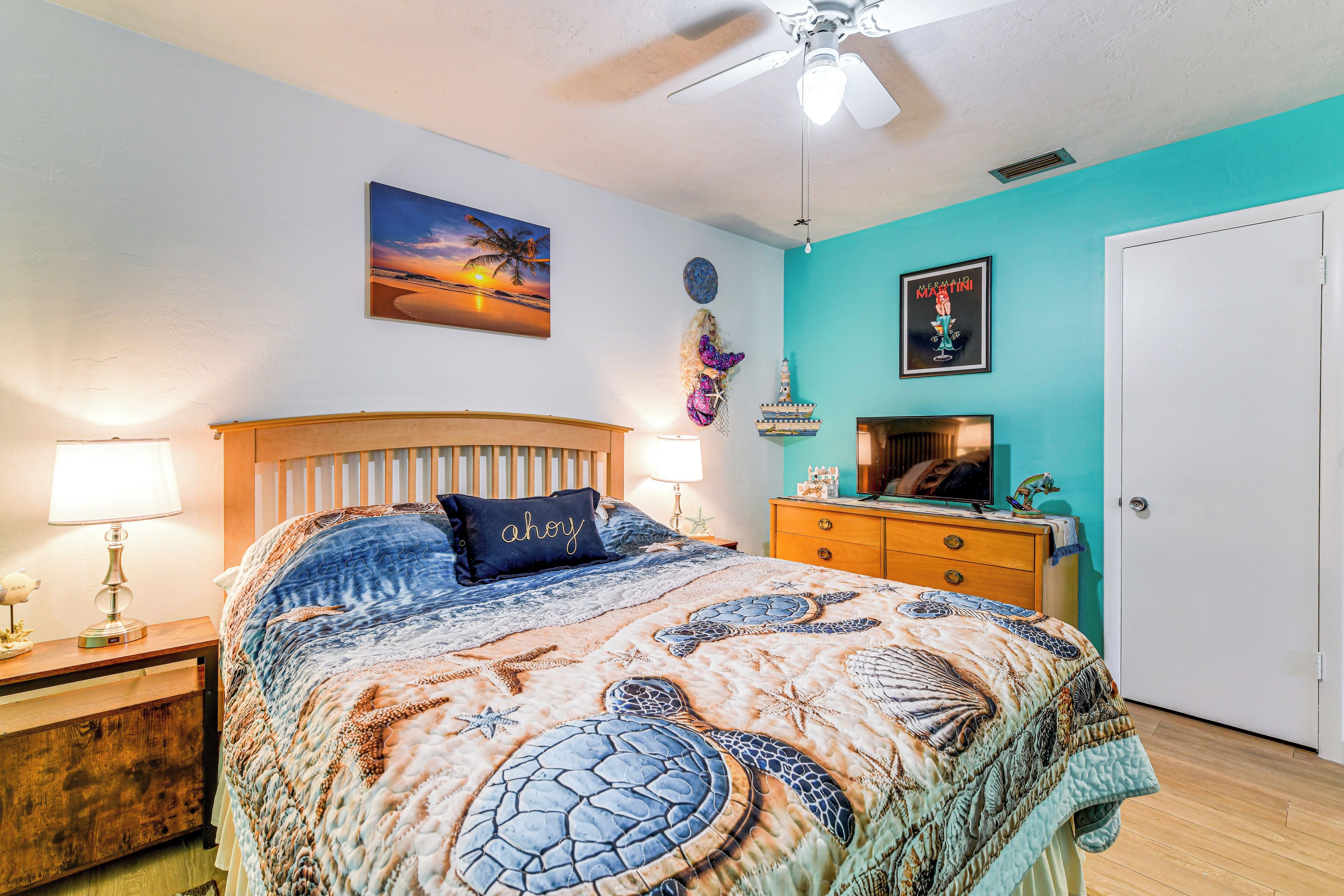 A bedroom with a bed, nightstands, a dresser, and a ceiling fan.