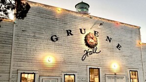 Un bâtiment dont la façade porte l’inscription « GRUENE Hall », orné d’une grande guirlande décorative et doté de nombreuses fenêtres.