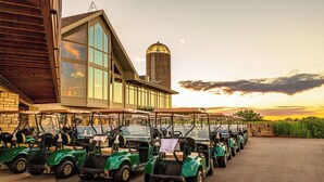 A row of golf carts parked in front of a building with large windows and a silo in the background. - Amazing Golf Views, Fireplace & Pool Access! (Galena)