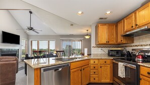 A modern kitchen with wooden cabinets, stainless steel appliances, and a built-in dishwasher. - Amazing Golf Views, Fireplace & Pool Access! (Galena)