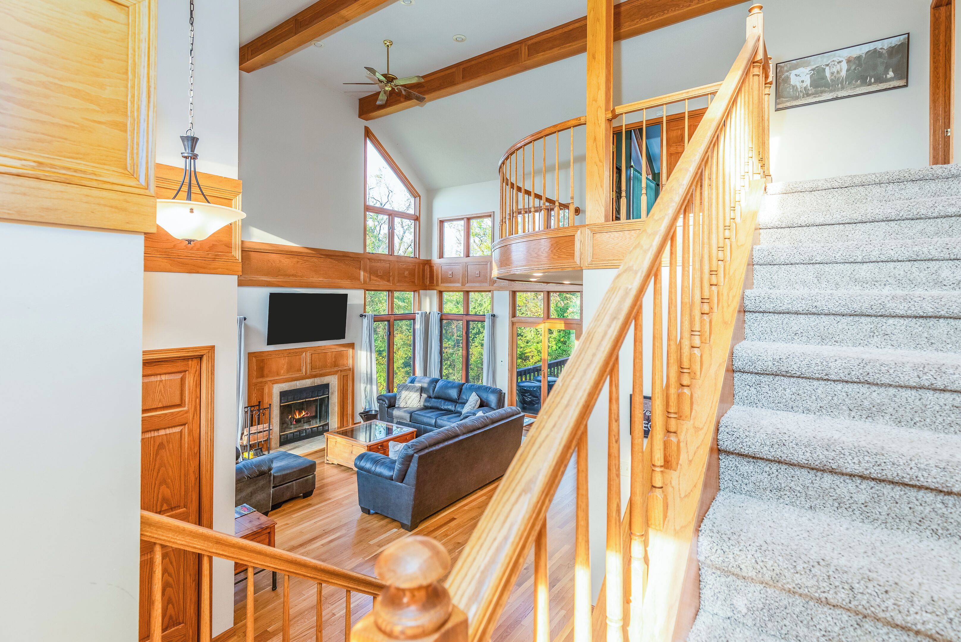 A spacious living area with a fireplace, a large sofa, and a staircase leading to an upper level.