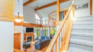 A spacious living area with a fireplace, a large sofa, and a staircase leading to an upper level. - Longwood - Wood Burning Fireplace - Hot Tub - Pool Table - Arcade Game (Galena)